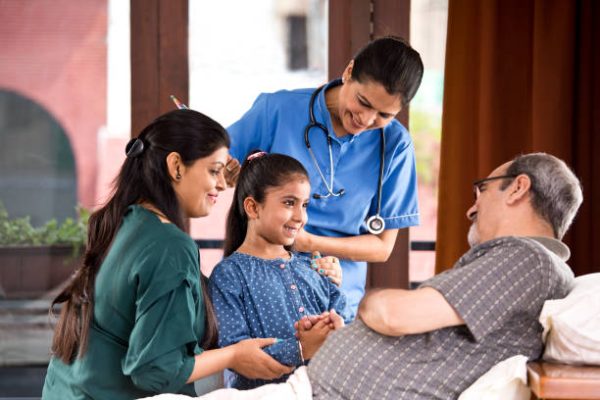 Female nurse and family with senior patient at home